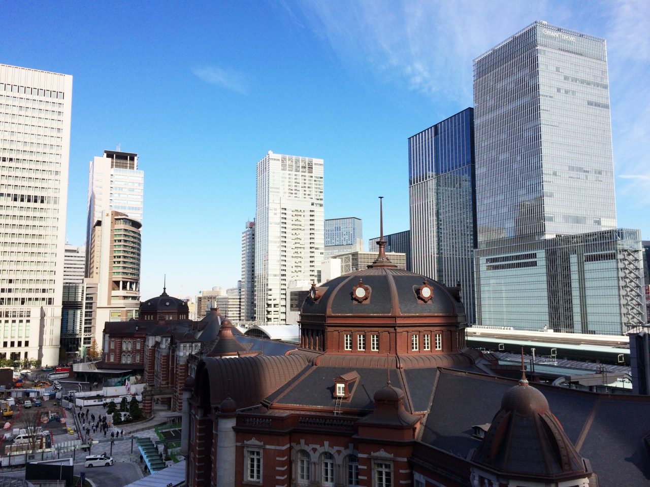 JPタワーから眺めた東京駅丸の内駅舎と高層ビル街の写真